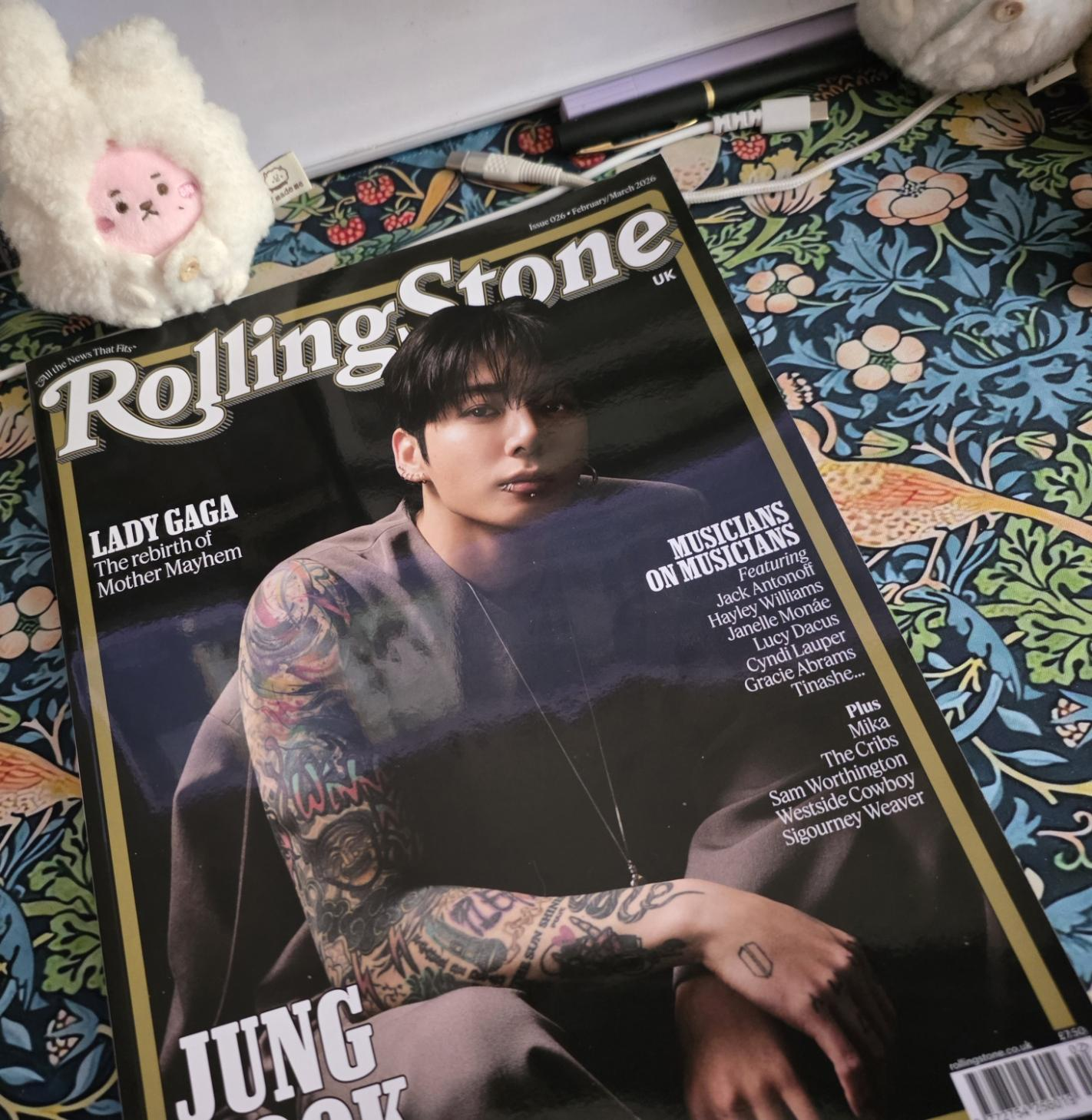 Jungkook on the cover of Rolling Stone, on my desk, with a tiny Kooky plushie observing in the background.