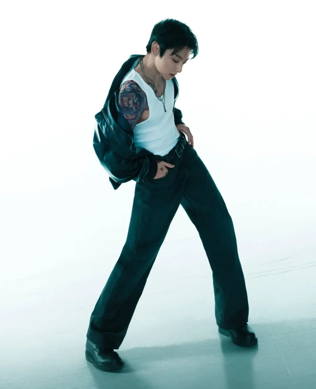 photo of Jungkook from the recent CK campaign (wearing a black jacket, white sleeveless shirt, black jeans, black boots, body art, and pendants) and looking agile