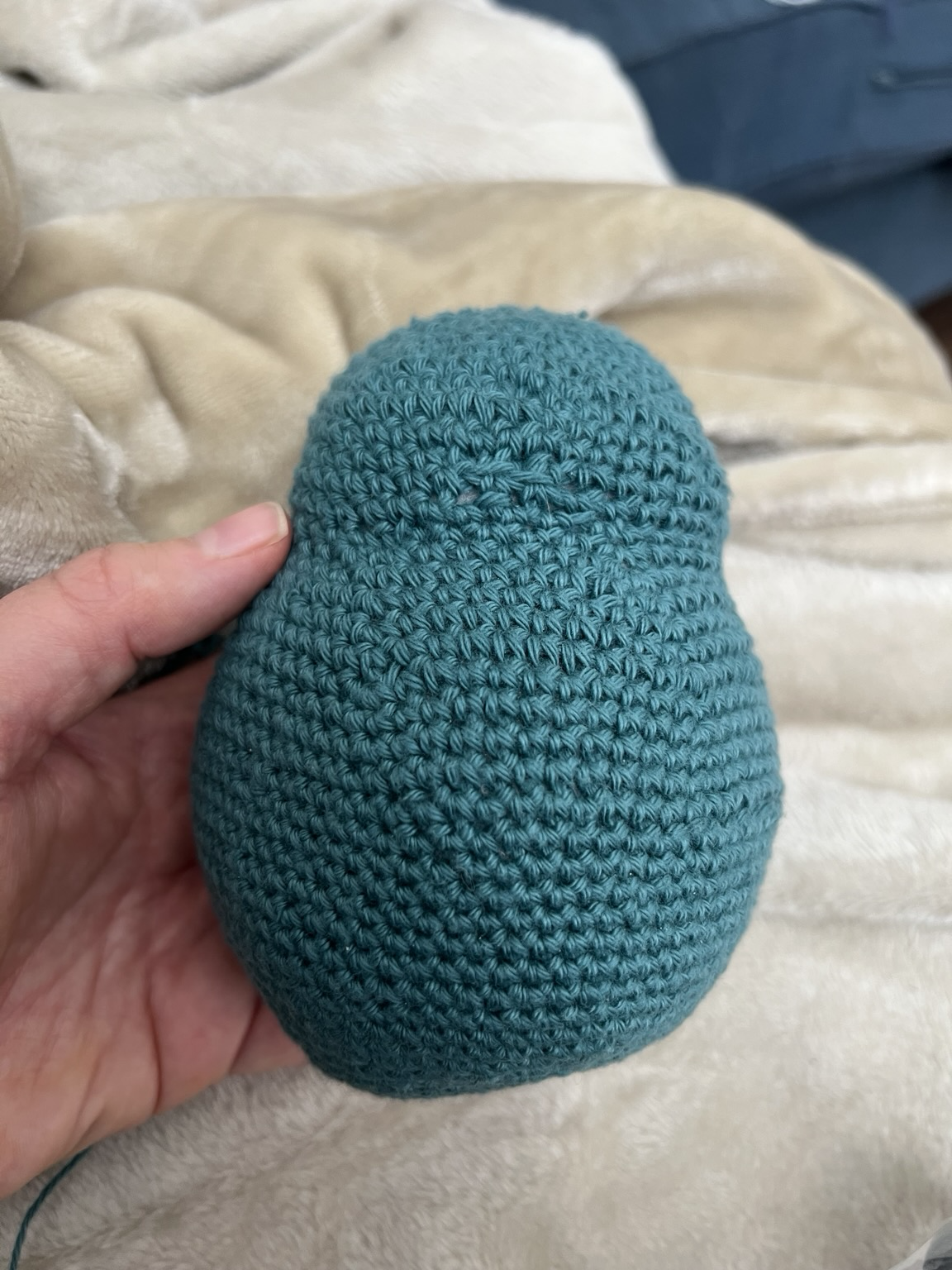 Crochet green jelly bean shaped item that is about the size of a hand. It may eventually be snorlax