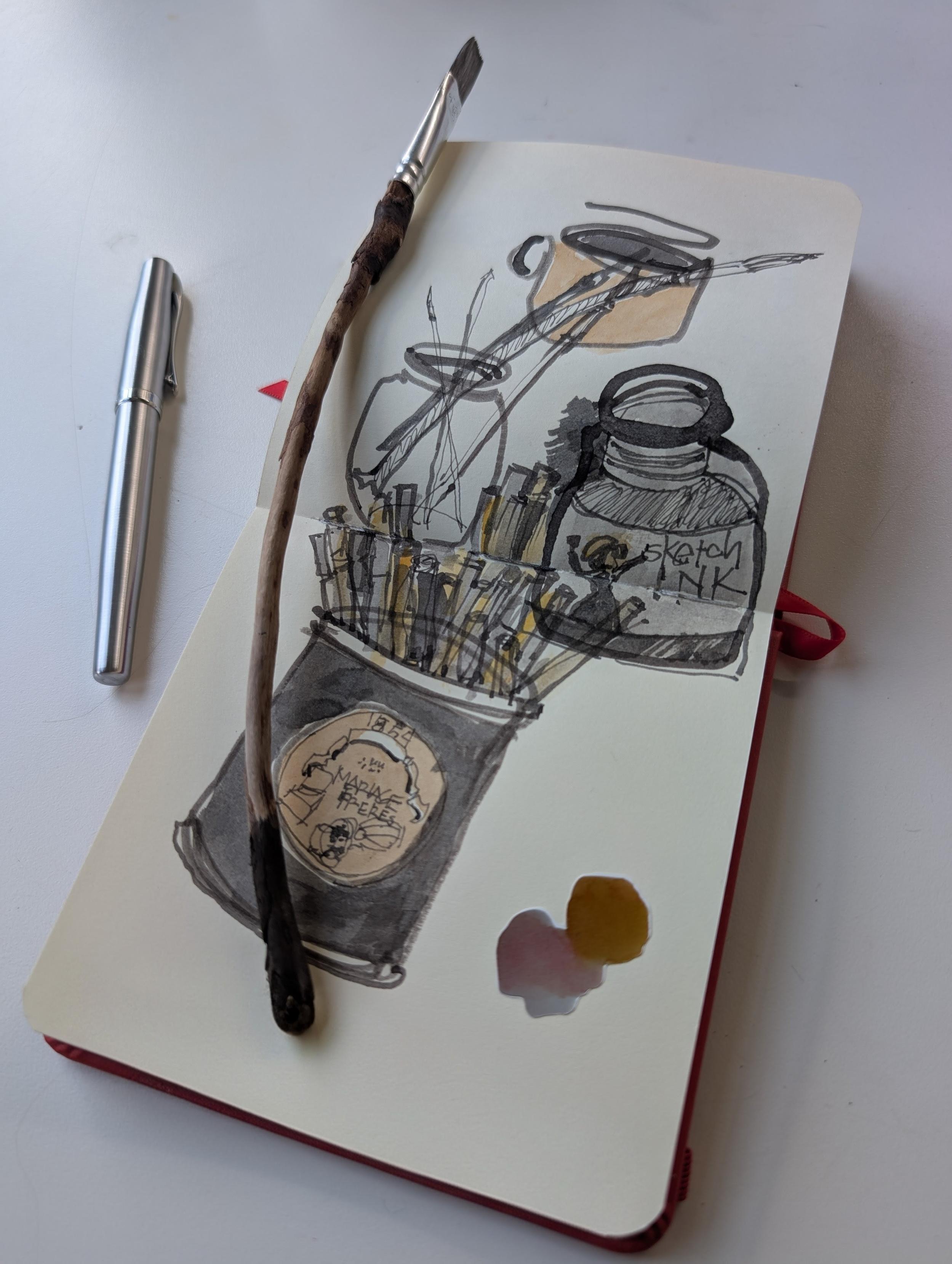 view of my tabletop and sketchbook
a slightly curved thin wood stick with a flat head brush 
a silvery metal fountain pen
illustrations of cups and jars