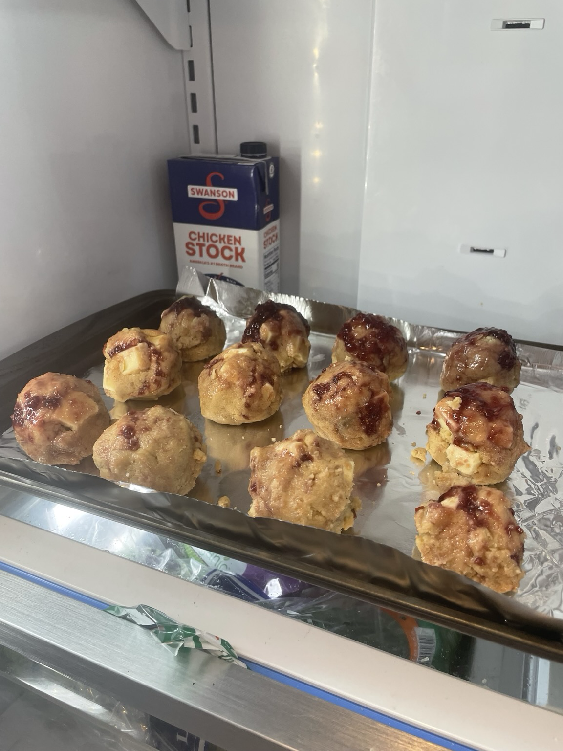 Balls of jam & butter toast cookies on an aluminum foiled sheet