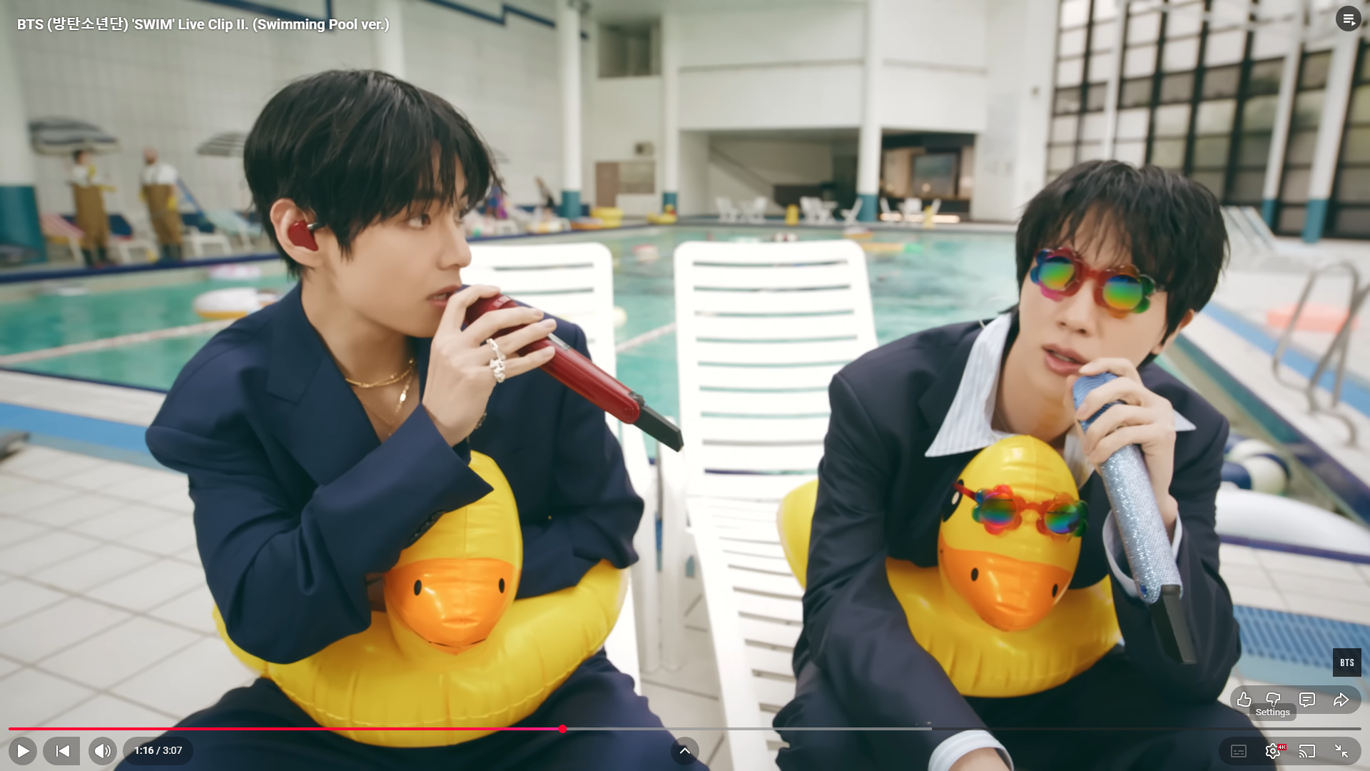 Jin and Tae in the BTS Swim Poolside MV - wearing yellow duck floatie rings. Jin is wearing ridiculous red sunglasses.