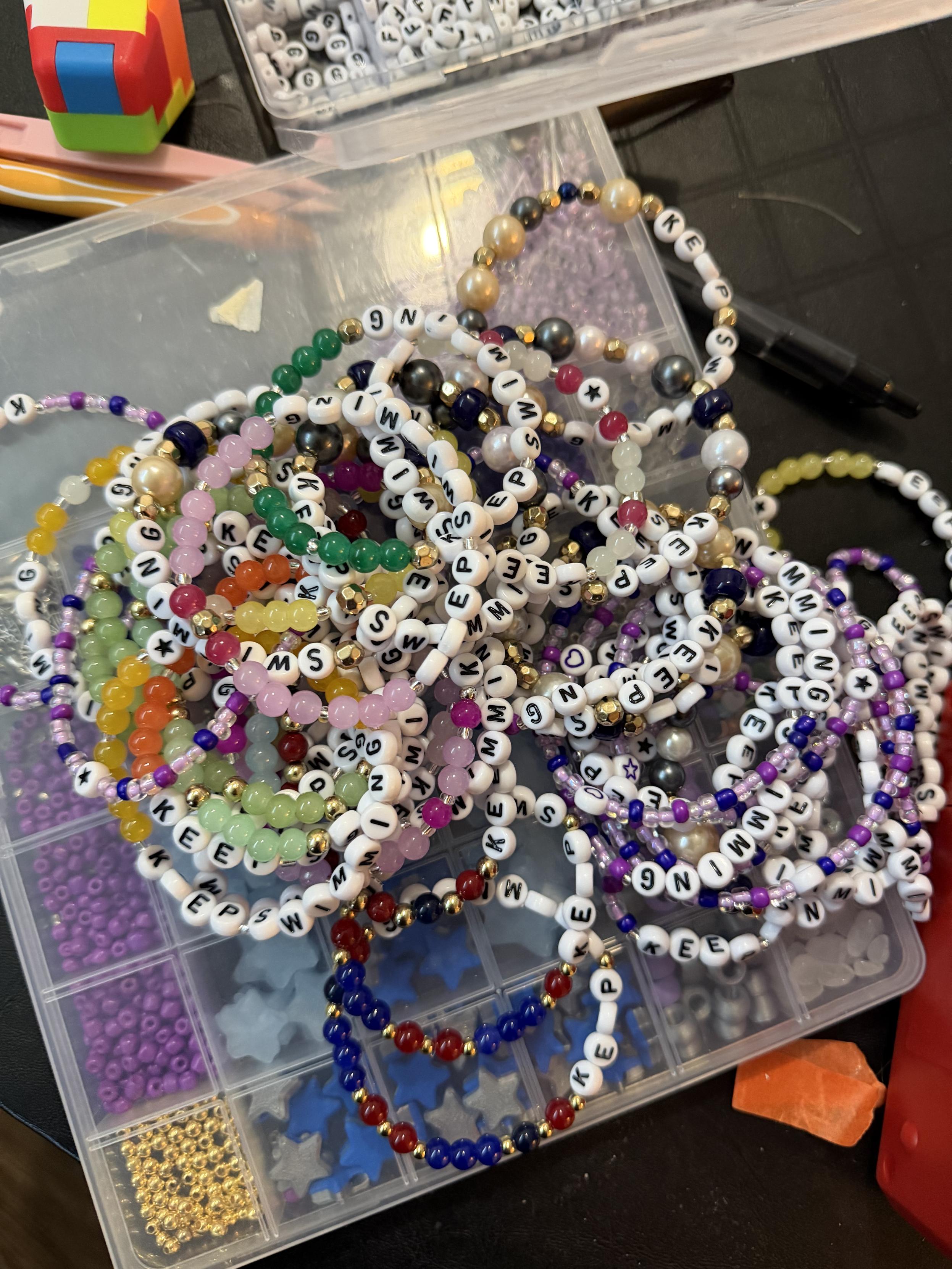 a pile of colorful friendship bracelets that say "keep swimming"