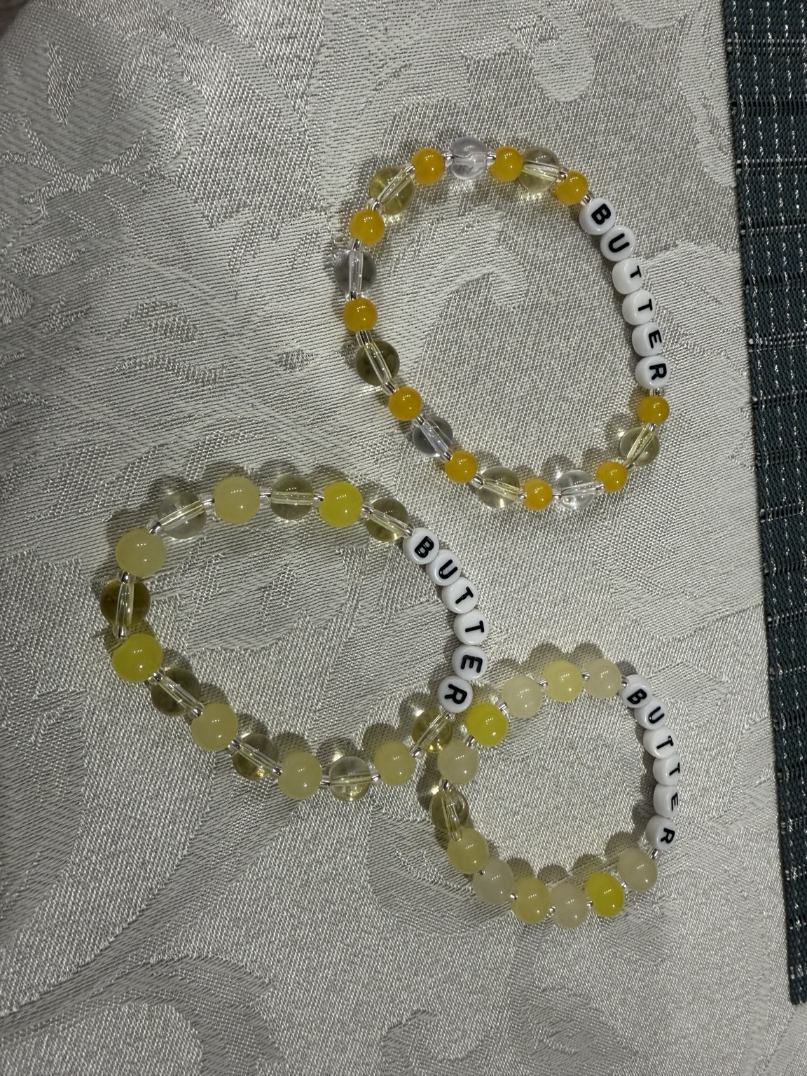 3 bead friendship bracelets that say BUTTER and have glass beads that are yellow